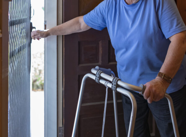 Senior Woman With a Walking Frame Answering the Door at Home