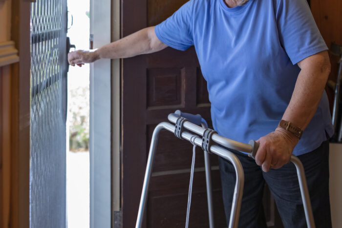 Senior Woman With a Walking Frame Answering the Door at Home