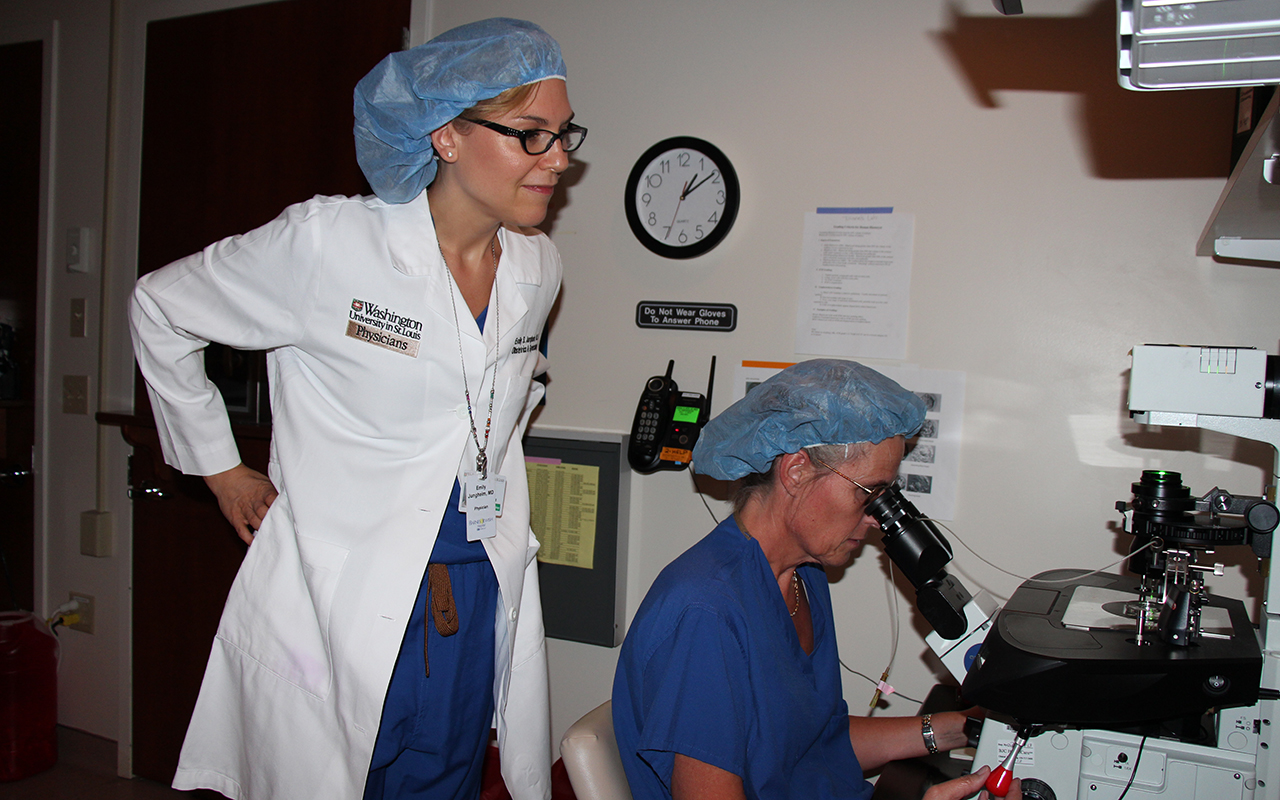 Emily Jungheim, MD, left, observes as Mary Bade uses assisted reproductive technology to inject a single sperm into an egg. Jungheim, MD, treats women with infertility, polycystic ovary syndrome, endometriosis and other conditions.