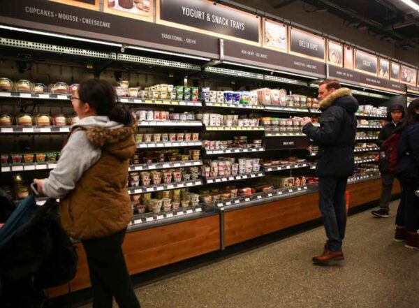 Customers browse the yogurt and deli sections in a grocery store