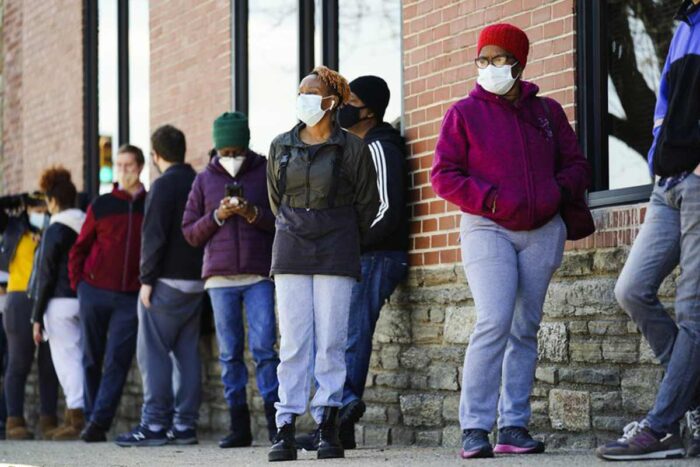 People wearing masks wait in line outside for COVID-19 vaccinations