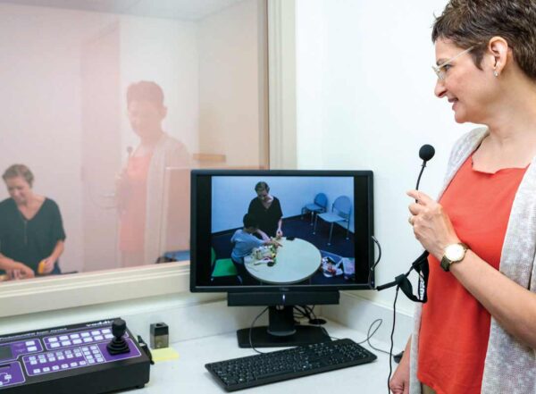 Joan Luby, MD, observes a parent and child through a one-way mirror and, using a microphone and earpiece.