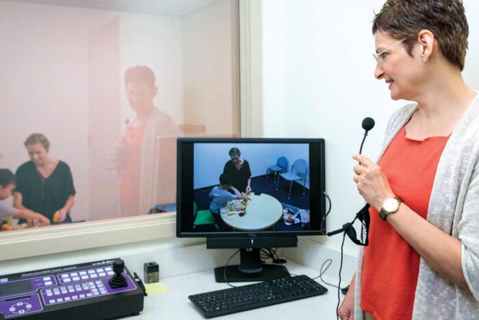 Joan Luby, MD, observes a parent and child through a one-way mirror and, using a microphone and earpiece.