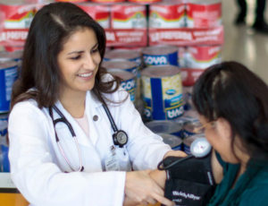 Plá giving a woman a free health screening at a Hispanic grocery store in St. Louis