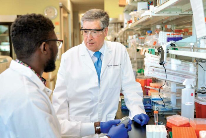Robert D. Schreiber, PhD, right, consults with doctoral student Samuel O. Ameh in a lab.